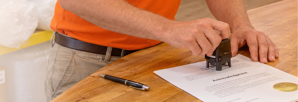 Notary public stamping document at Oh Ship! counter in Tamarac, FL.